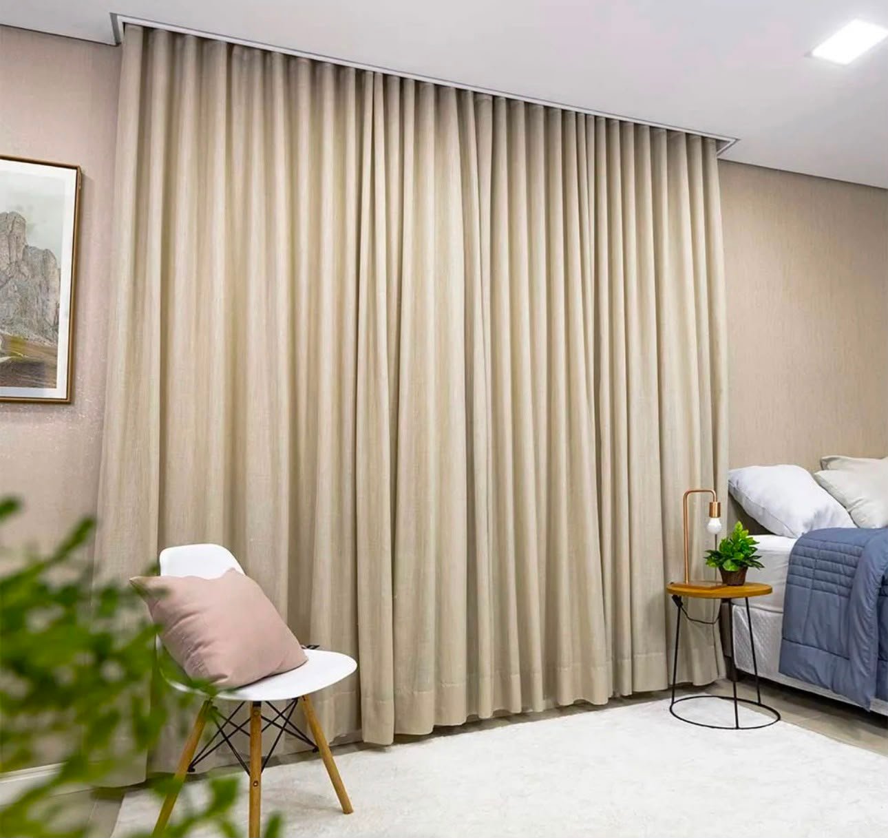 Cortina de linho bege em quarto de casal com poltrona branca